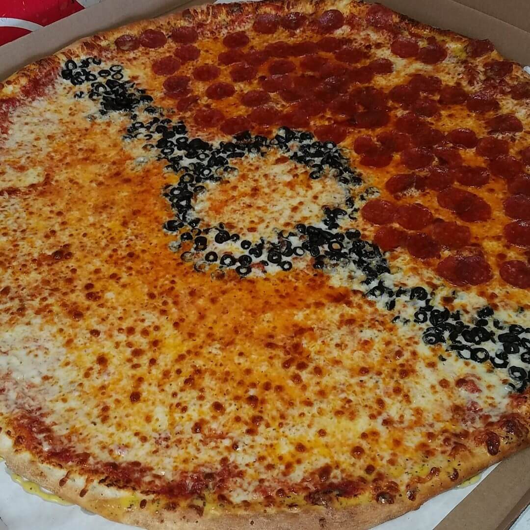 Large pizza with a musical note design made of olives and pepperoni.