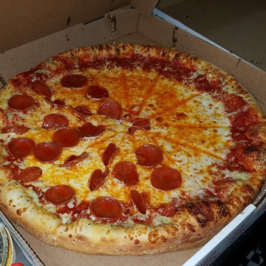 A large pepperoni pizza with one slice removed.